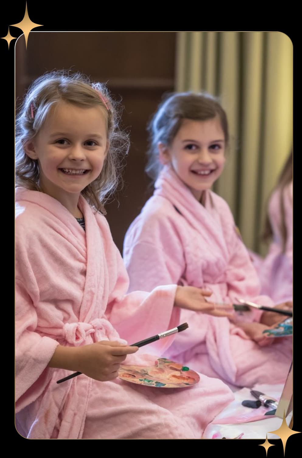Two children holding paintbrushes and palettes during a painting activity